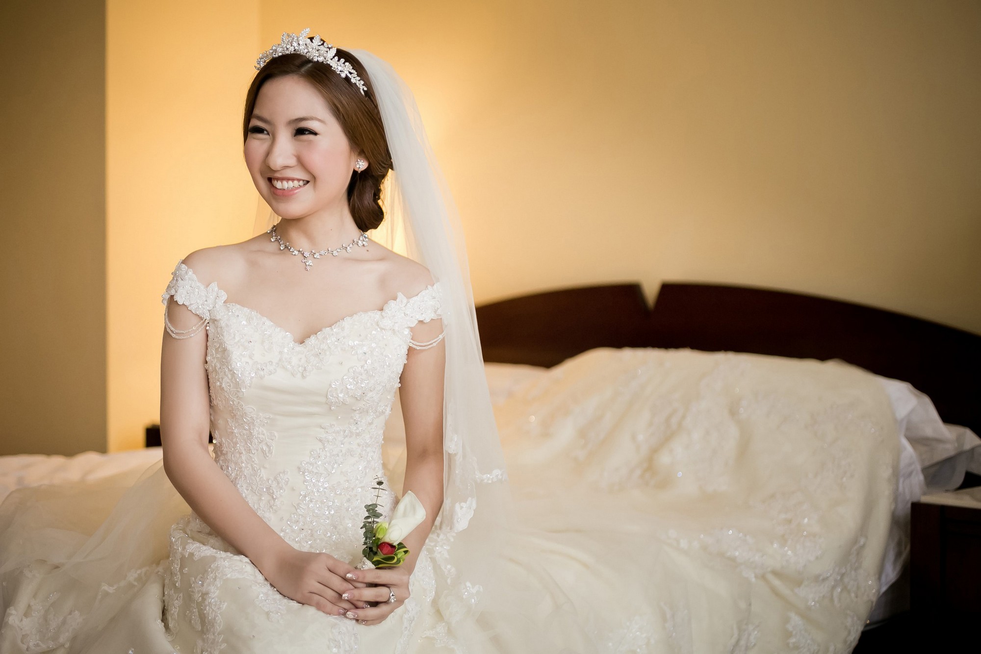 A beautiful bride in a wedding dress, captured in a creative photography style, sitting gracefully on a bed