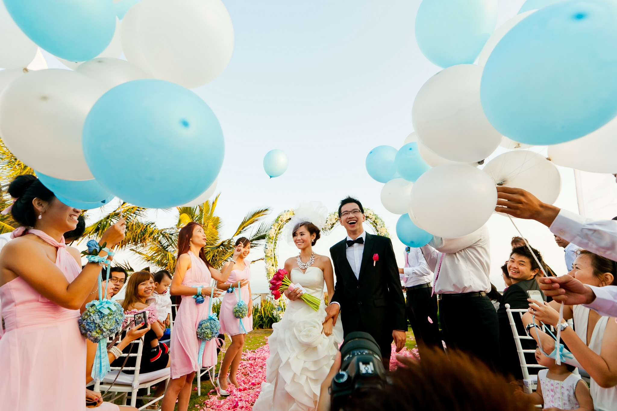 Bride and groom walk down aisle with blue and white balloons at bridal wedding photography in Singapore.