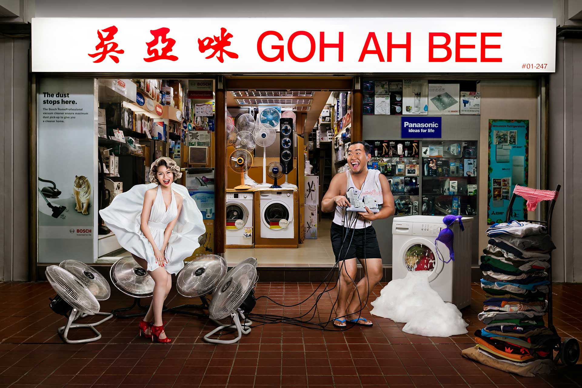 A couple posing humorously in front of a laundry shop during a creative photoshoot.