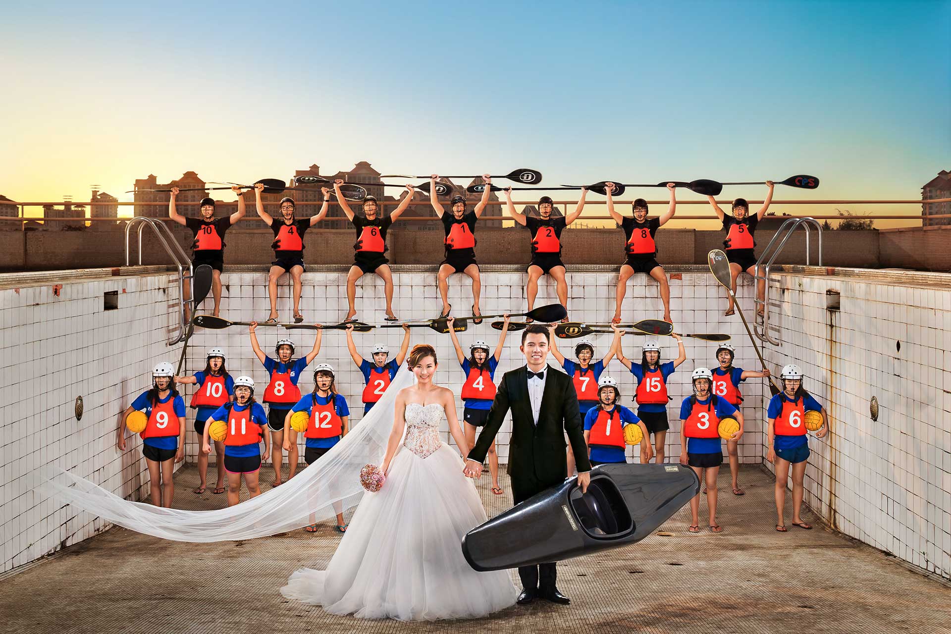 A bride and groom, along with their wedding party, strike a pose in a creative photoshoot that includes a swimmer.