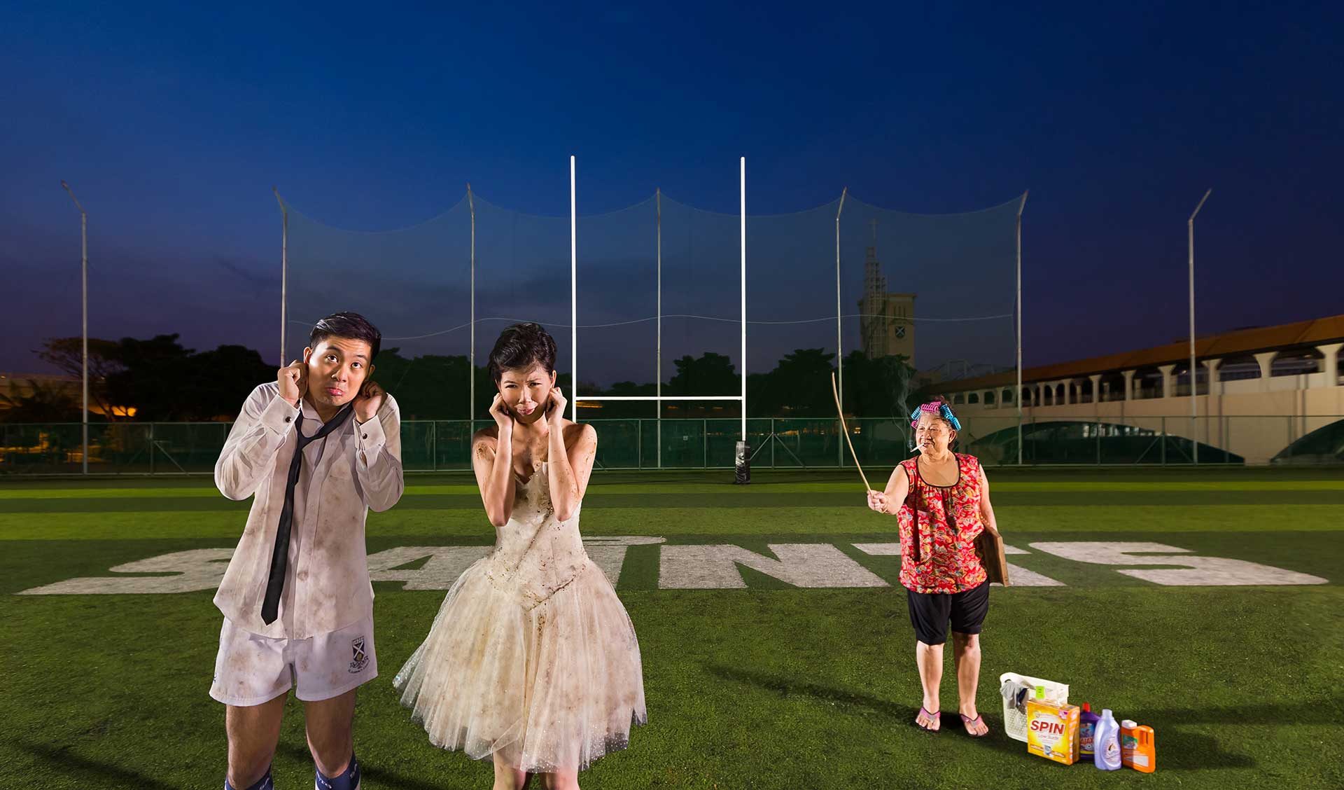 A couple in a regretful pose during a creative photoshoot on a football field.